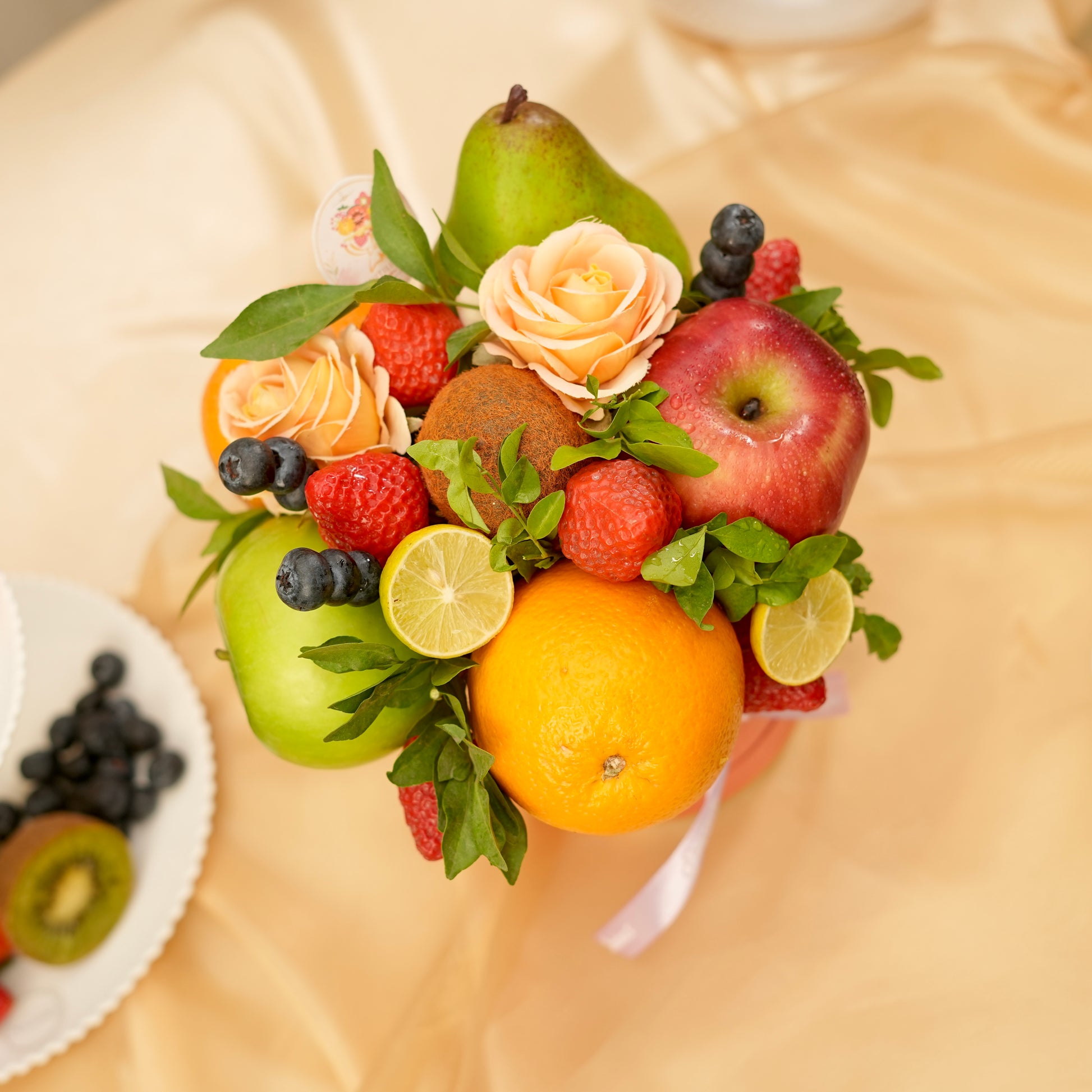 Fruit and flower arrangement on a beige surface