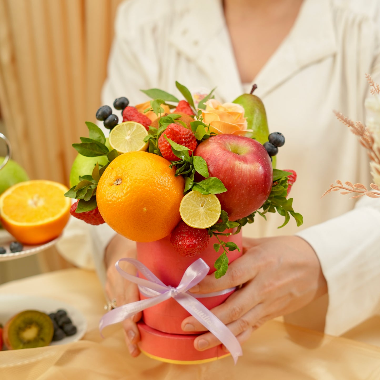 Bouquet made of fruits and flowers held by a person, with a focus on oranges, apples, and other fruits.