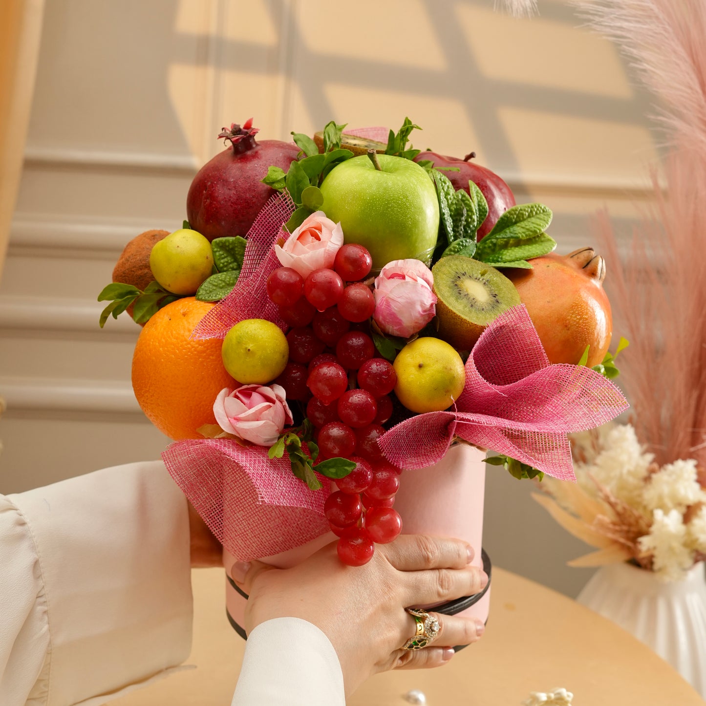 Bouquet of fruits and flowers held by a person with a blurred background