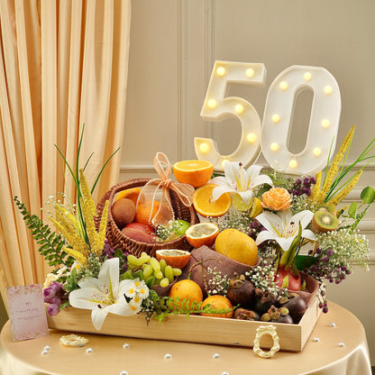 Premium Golden Jubilee fruit hamper featuring oranges, passion fruit, mangosteen, lilies, and floral styling for a 50th celebration.