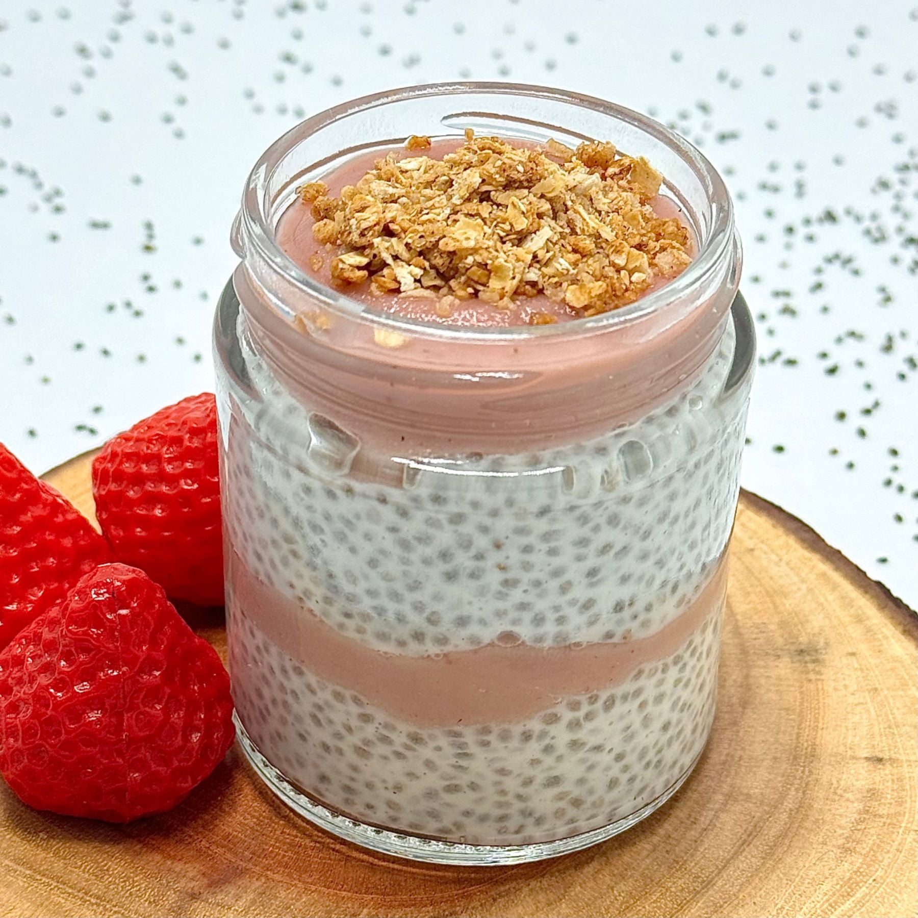 Glass jar with layered dessert on a wooden board with strawberries