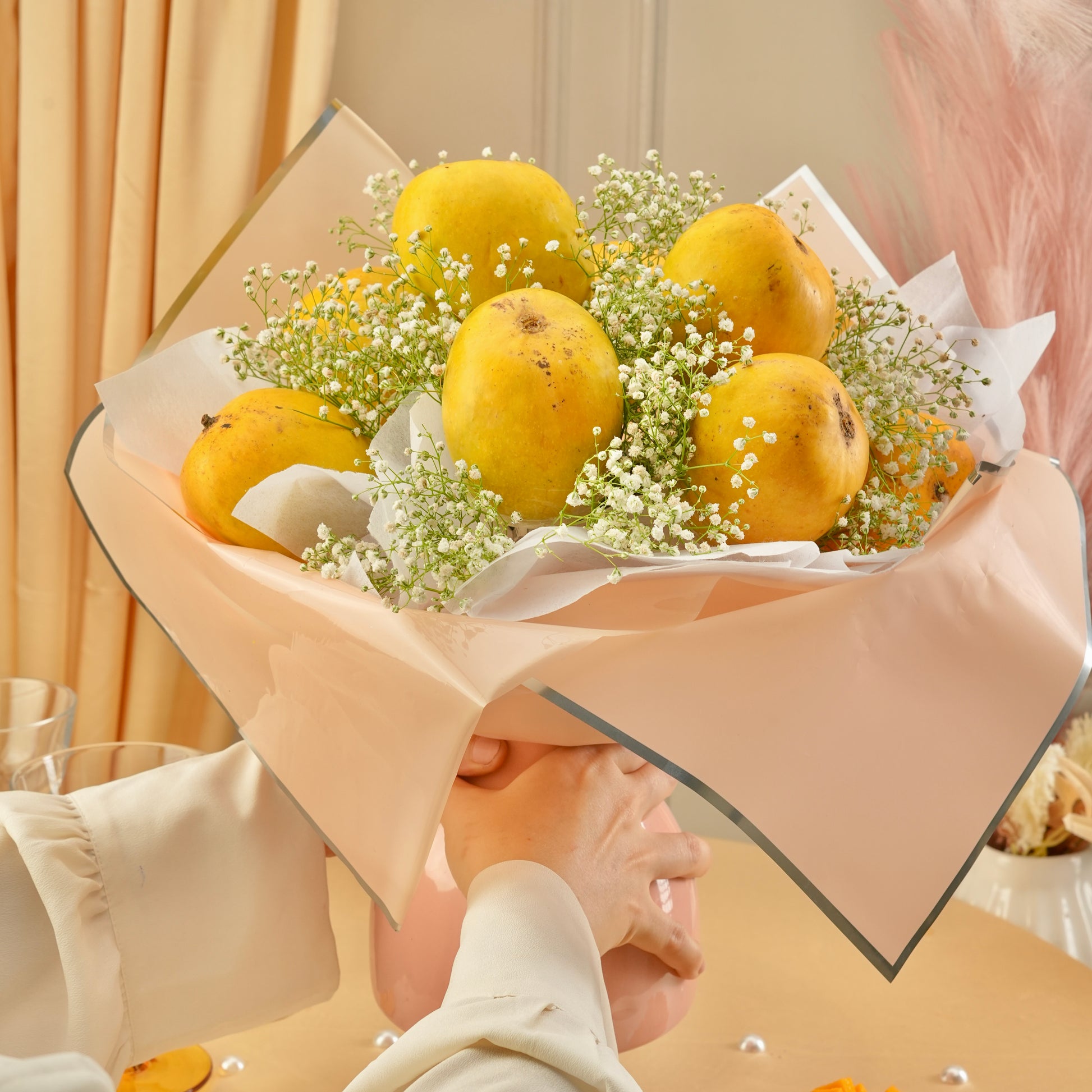 Premium Mango Blossom fruit bouquet featuring ripe mangoes arranged artistically with floral accents in a soft pink aesthetic setup.