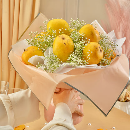 Premium Mango Blossom fruit bouquet featuring ripe mangoes arranged artistically with floral accents in a soft pink aesthetic setup.