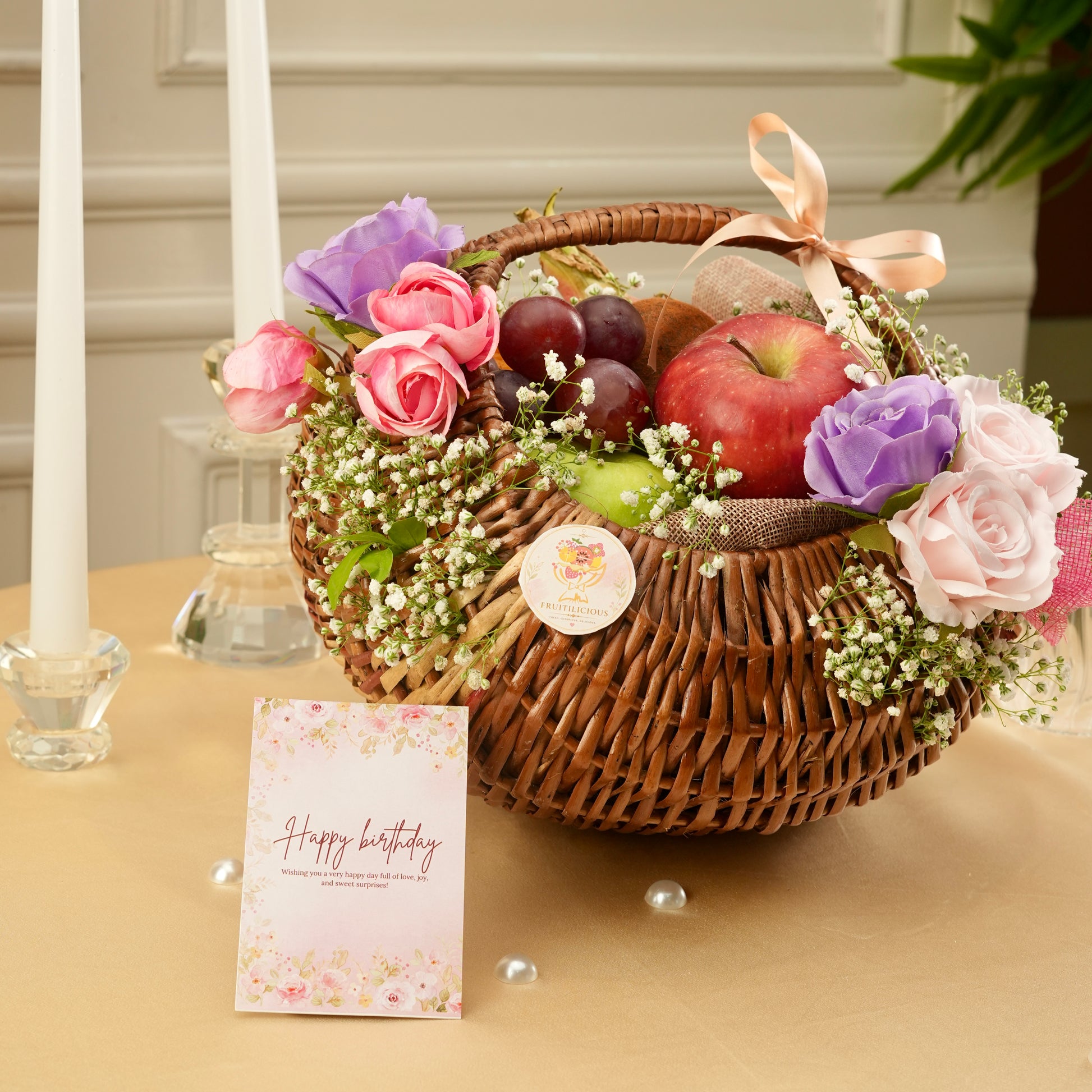 Decorative fruit basket with flowers and a birthday card on a table.