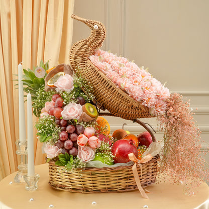 Decorative basket with flowers, fruits, and candles on a table.