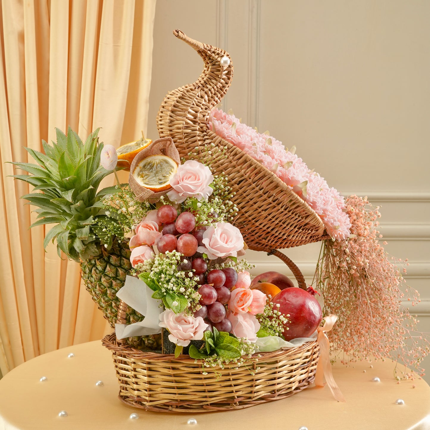 Decorative basket with fruits, flowers, and a pineapple on a table.
